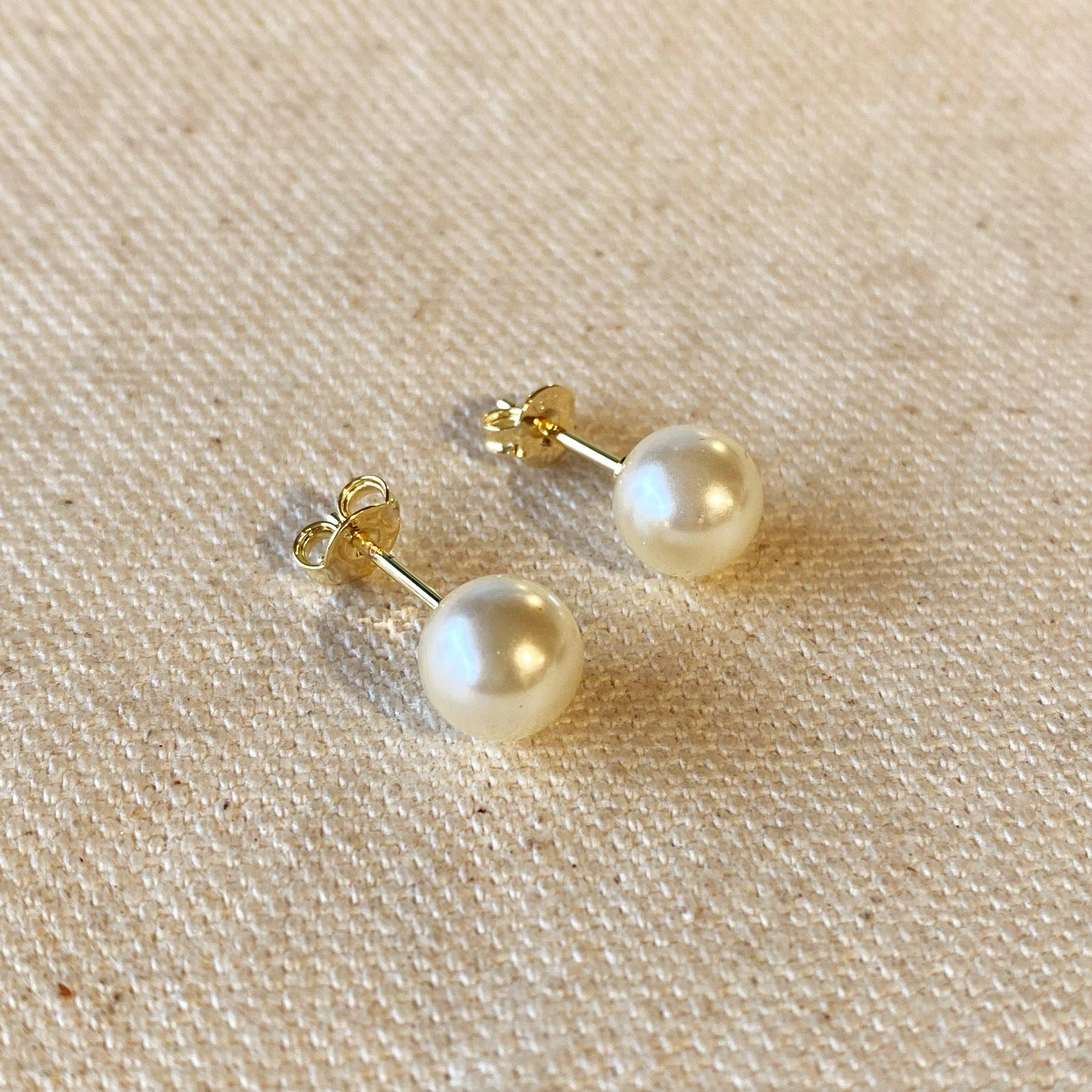 Pair of pearl earrings on a beige fabric background. Shop Rutledge Exchange for curated vintage and jewelry in Camden, SC.