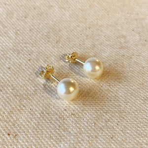 Pair of pearl earrings on a beige fabric background. Shop Rutledge Exchange for curated vintage and jewelry in Camden, SC.