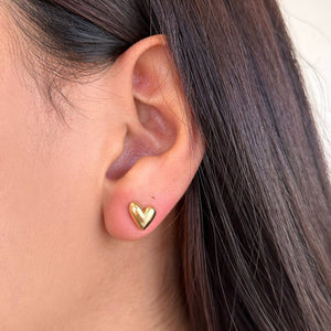 Gold heart-shaped earring worn by a person with dark hair. Shop Rutledge Exchange for curated vintage and jewelry in Camden, SC