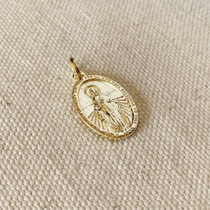Gold pendant with religious design on a beige fabric background. 
Shop Rutledge Exchange for curated vintage and jewelry in Camden, SC.&nbsp;