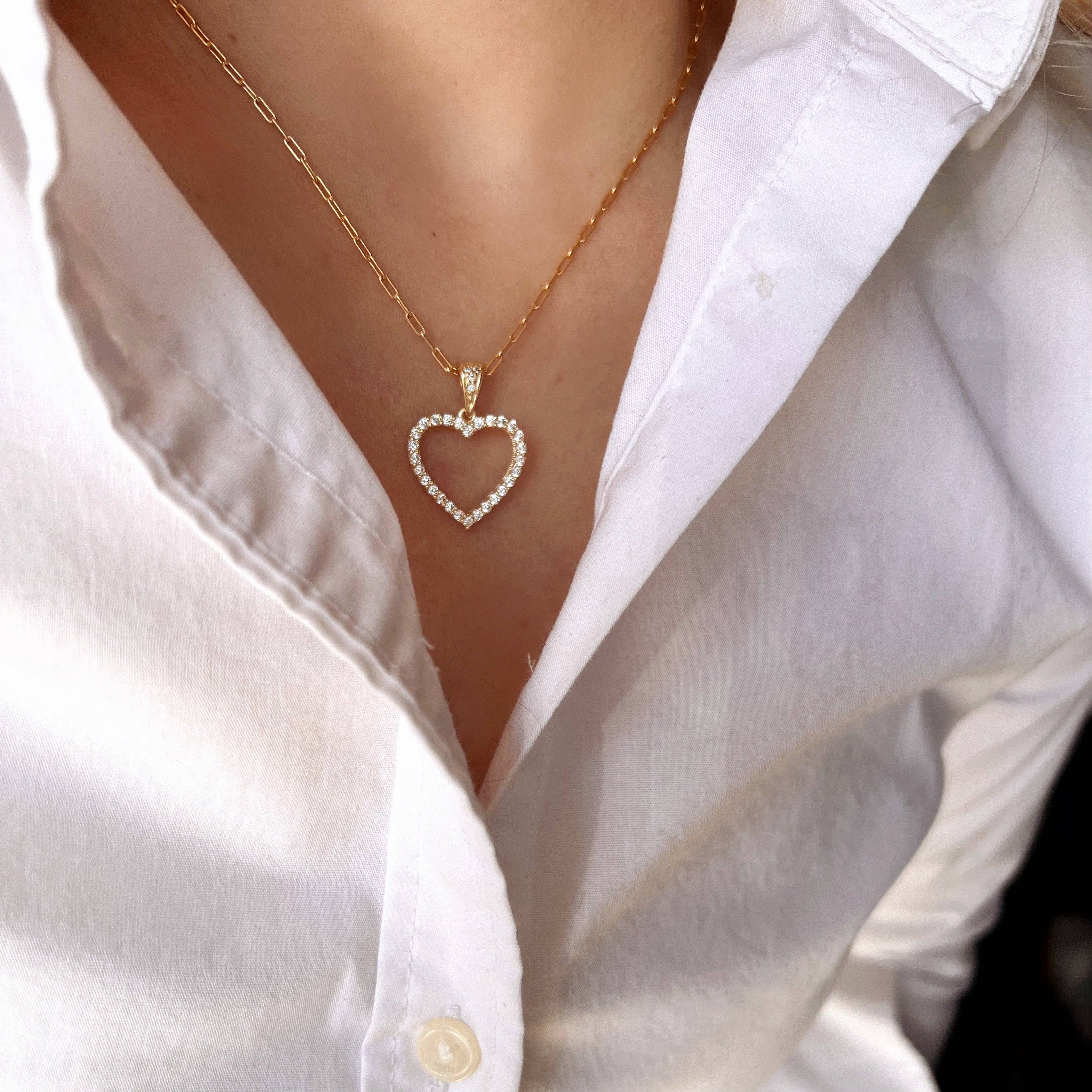 Gold necklace with a heart-shaped pendant worn by a person in a white shirt. Shop Rutledge Exchange for curated vintage and jewelry in Camden, SC.
