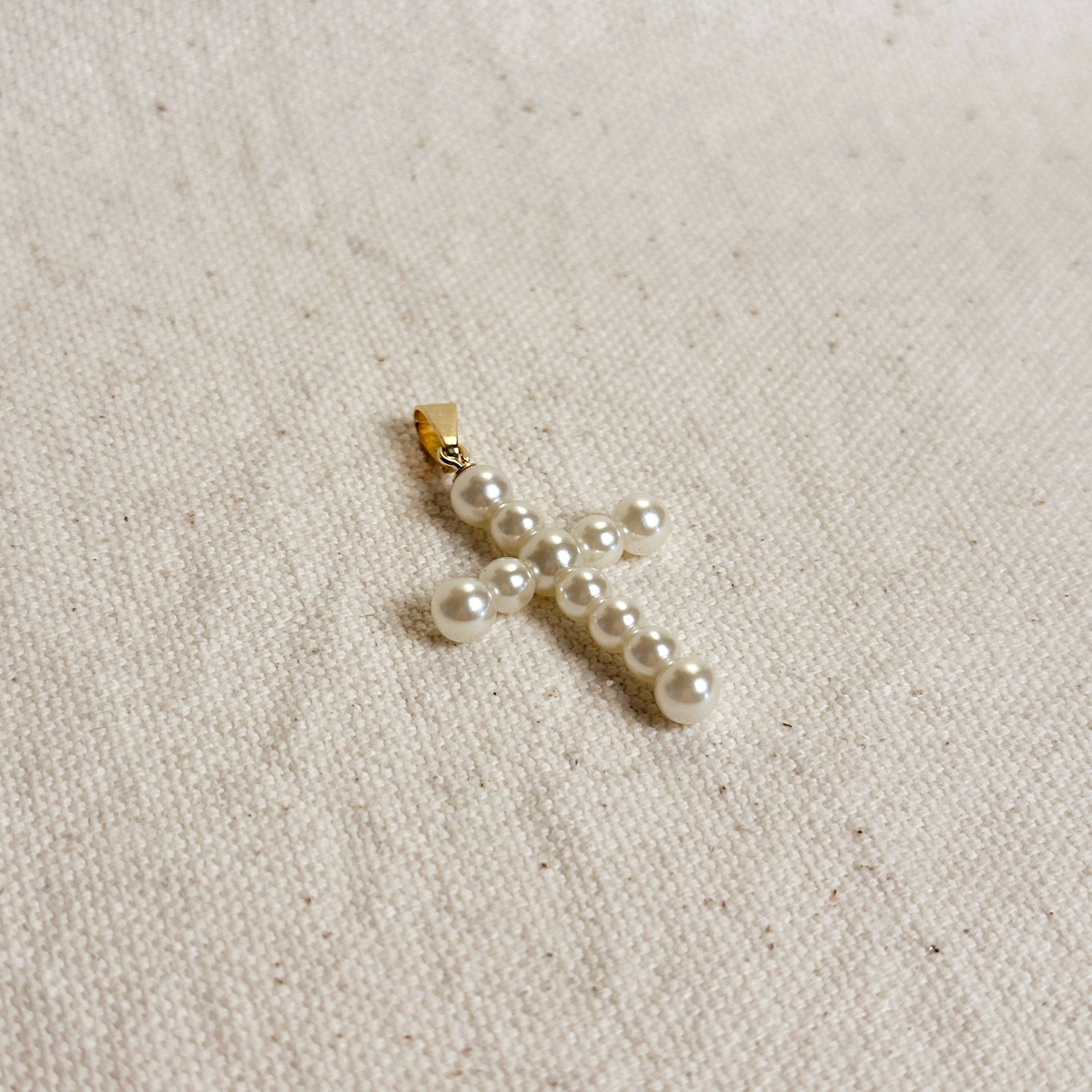Pearl cross pendant on a beige fabric background. Shop Rutledge Exchange for curated vintage and jewelry in Camden, SC.