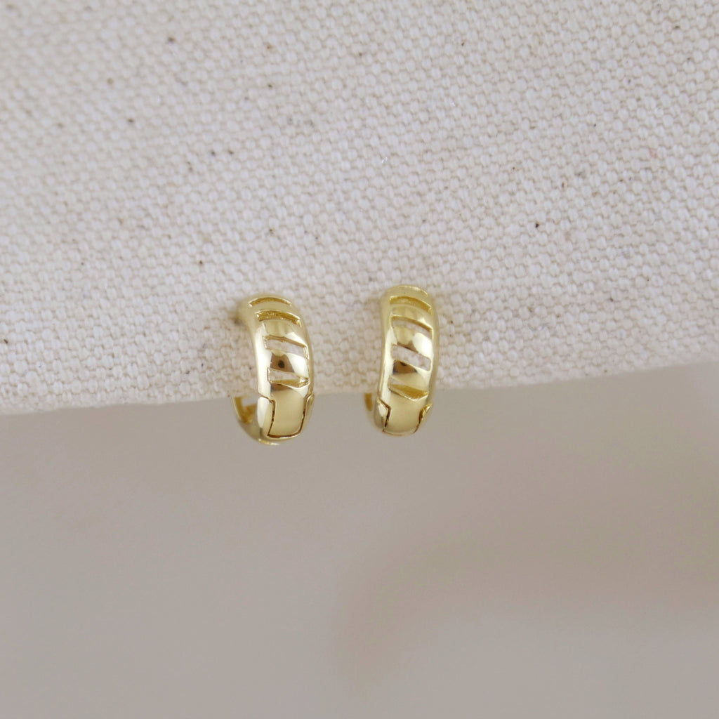 Pair of gold hoop earrings on a light fabric background. Shop Rutledge Exchange for curated vintage and jewelry in Camden, SC.