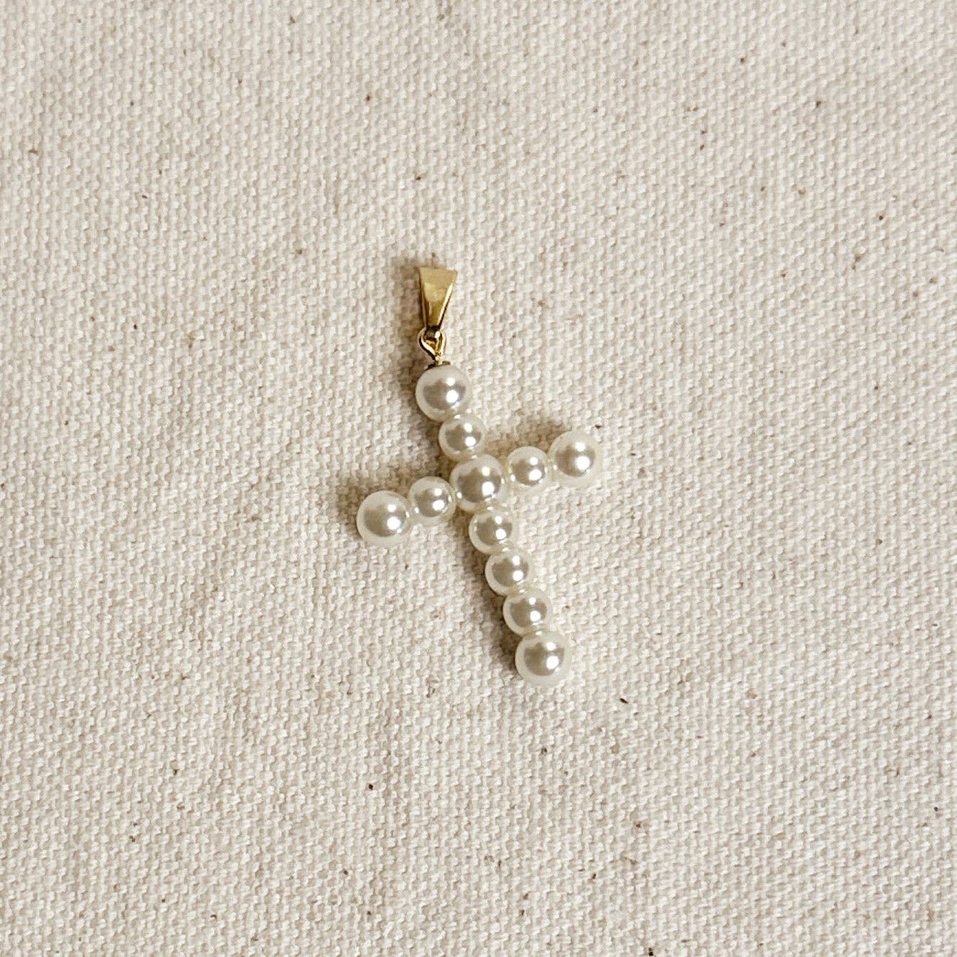 Pearl cross pendant on a beige fabric background Shop Rutledge Exchange for curated vintage and jewelry in Camden, SC.