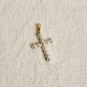 Pearl cross pendant on a beige fabric background Shop Rutledge Exchange for curated vintage and jewelry in Camden, SC.