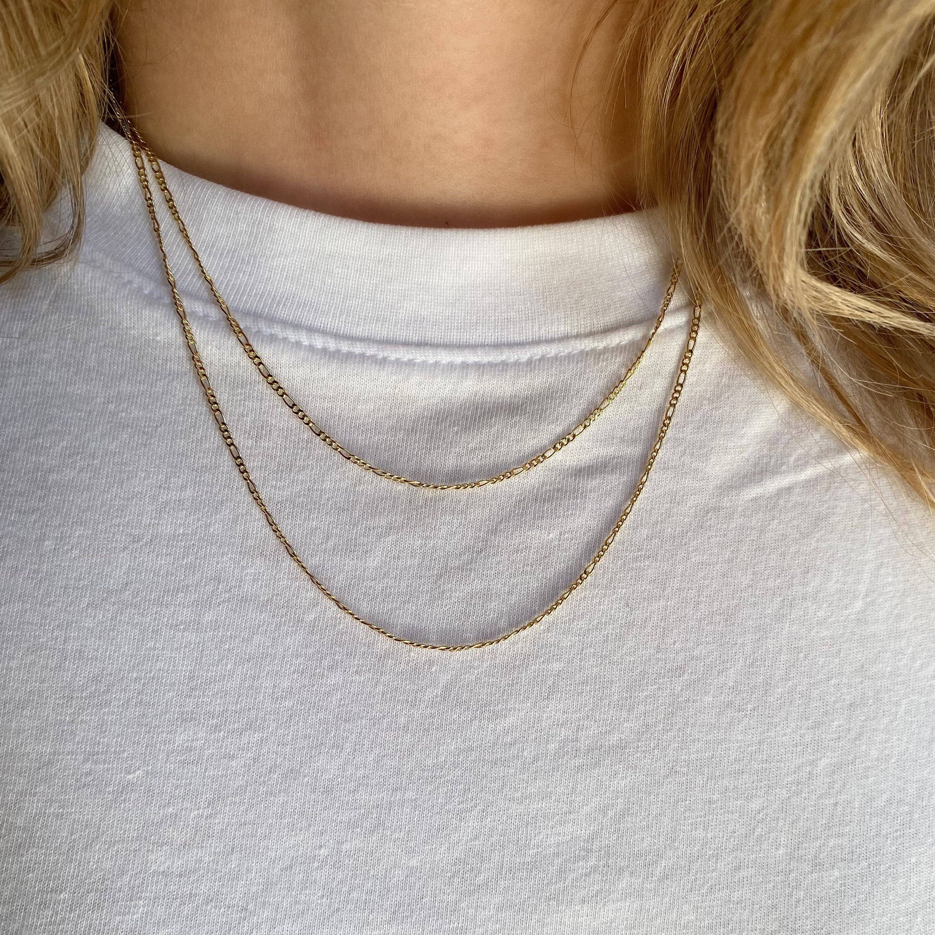Close-up of a person wearing a gold necklace on a white shirt