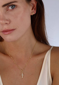 Close-up of a woman wearing gold cross necklace and earrings against a white background. Shop Rutledge Exchange for curated vintage and jewelry in Camden, SC