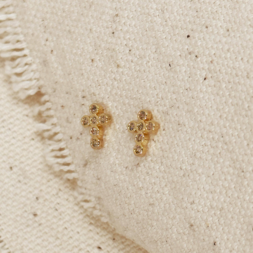 Gold cross-shaped earrings on a textured beige surface. 

Shop Rutledge Exchange for curated vintage and jewelry in Camden, SC.