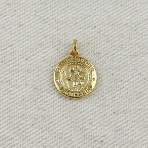 Gold pendant with 'St Christopher Protect Us' text on a textured beige background. Shop Rutledge Exchange for curated vintage and jewelry in Camden, SC.&nbsp;
