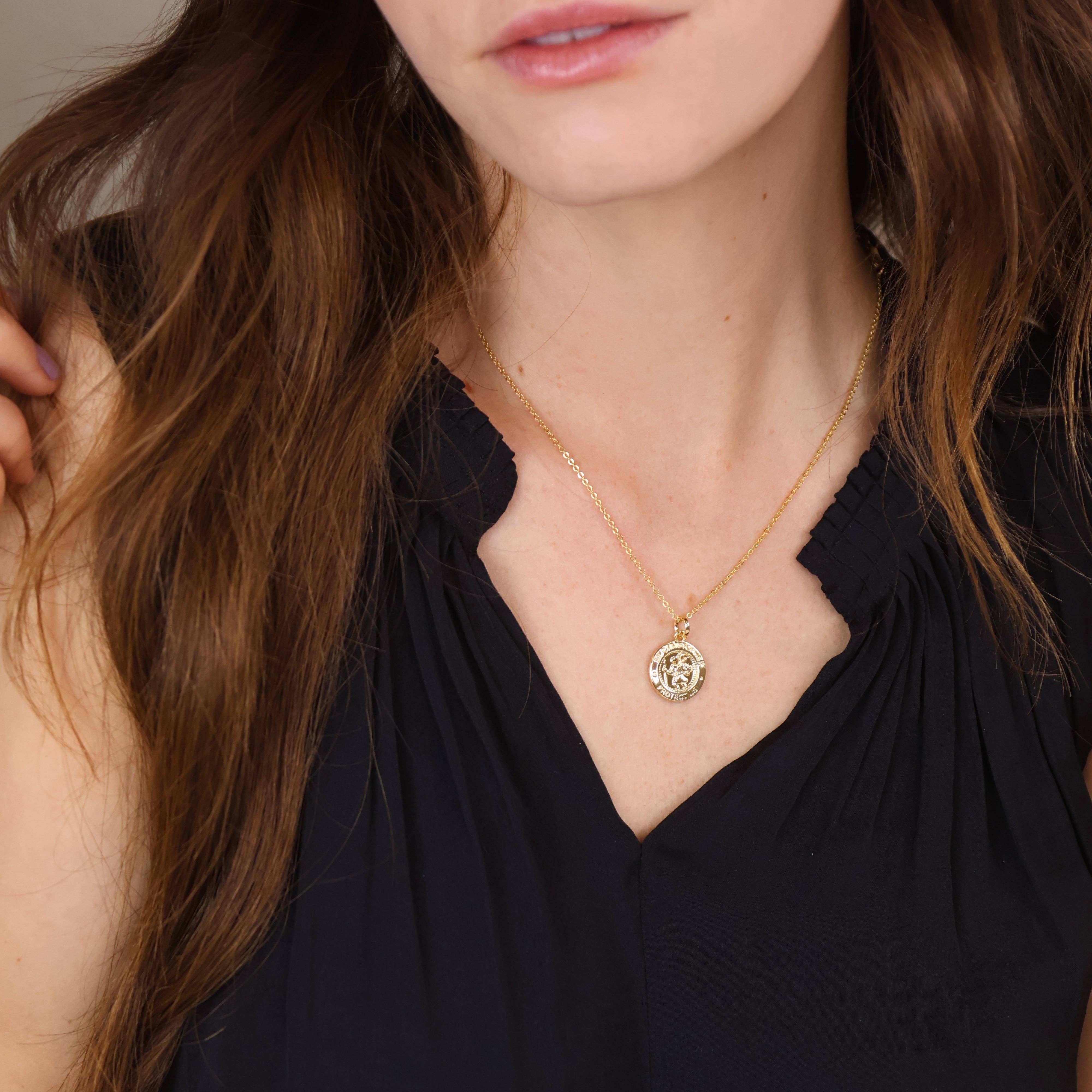 Woman wearing a gold necklace with a pendant against a neutral background. Shop Rutledge Exchange for curated vintage and jewelry in Camden, SC.&nbsp;