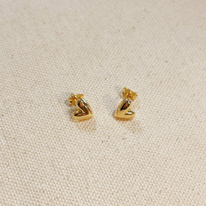 Gold heart-shaped earrings on a beige fabric background. Shop Rutledge Exchange for curated vintage and jewelry in Camden, SC.