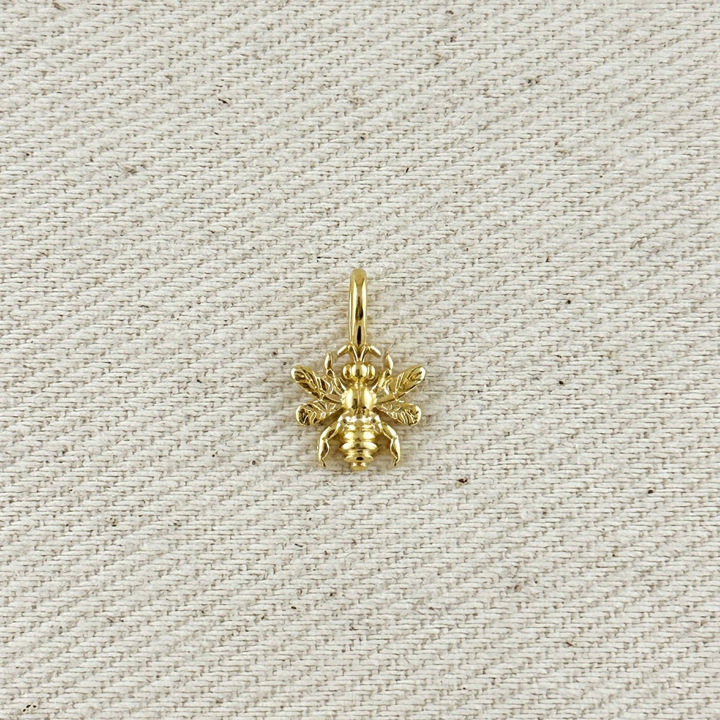 Gold bee pendant on a textured beige background. Shop Rutledge Exchange for curated vintage and jewelry in Camden, SC.&nbsp;