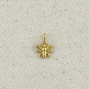 Gold bee pendant on a textured beige background. Shop Rutledge Exchange for curated vintage and jewelry in Camden, SC.&nbsp;