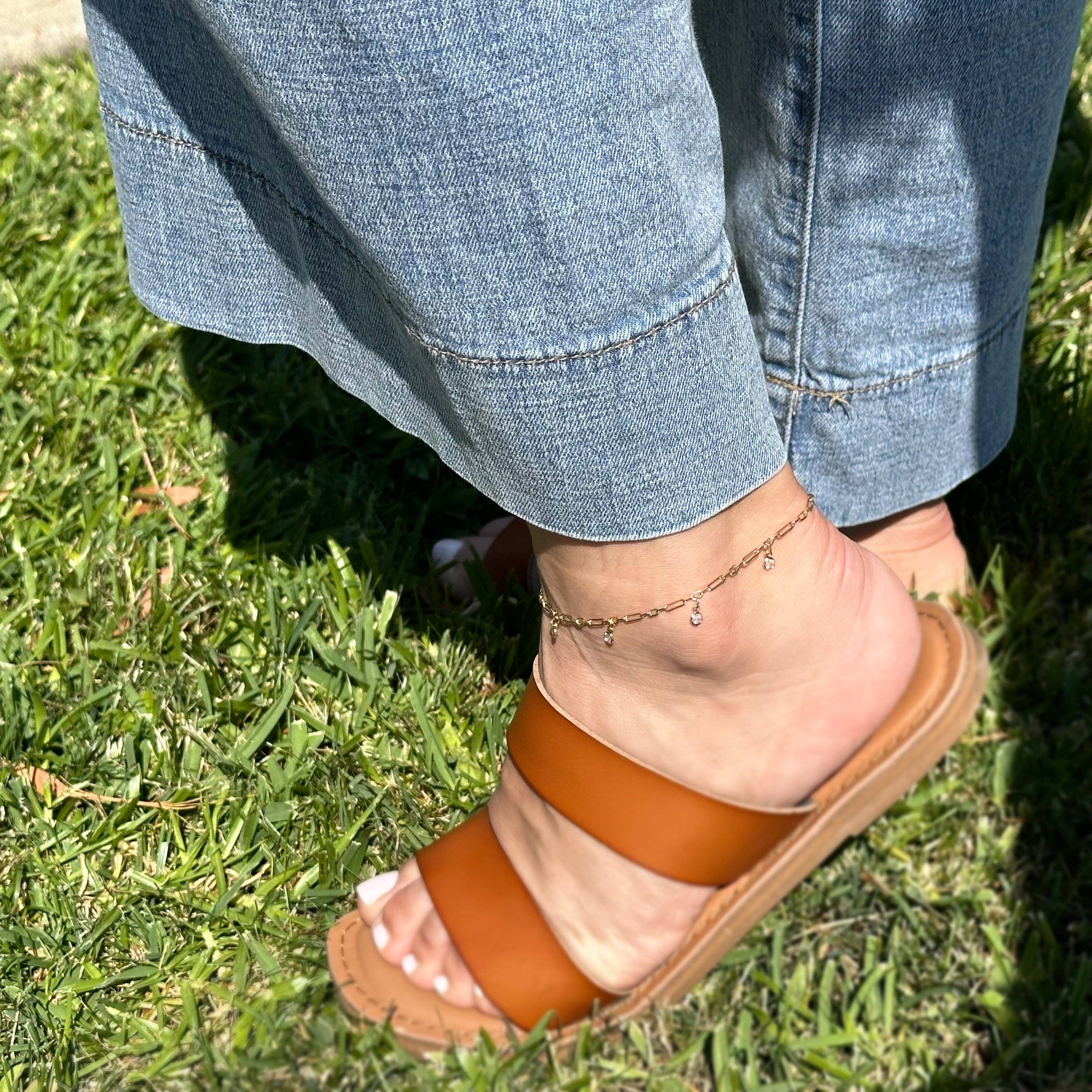 Brown sandal worn on a foot with blue jeans and grass in the background. Shop Rutledge Exchange for curated vintage and jewelry in Camden, SC.