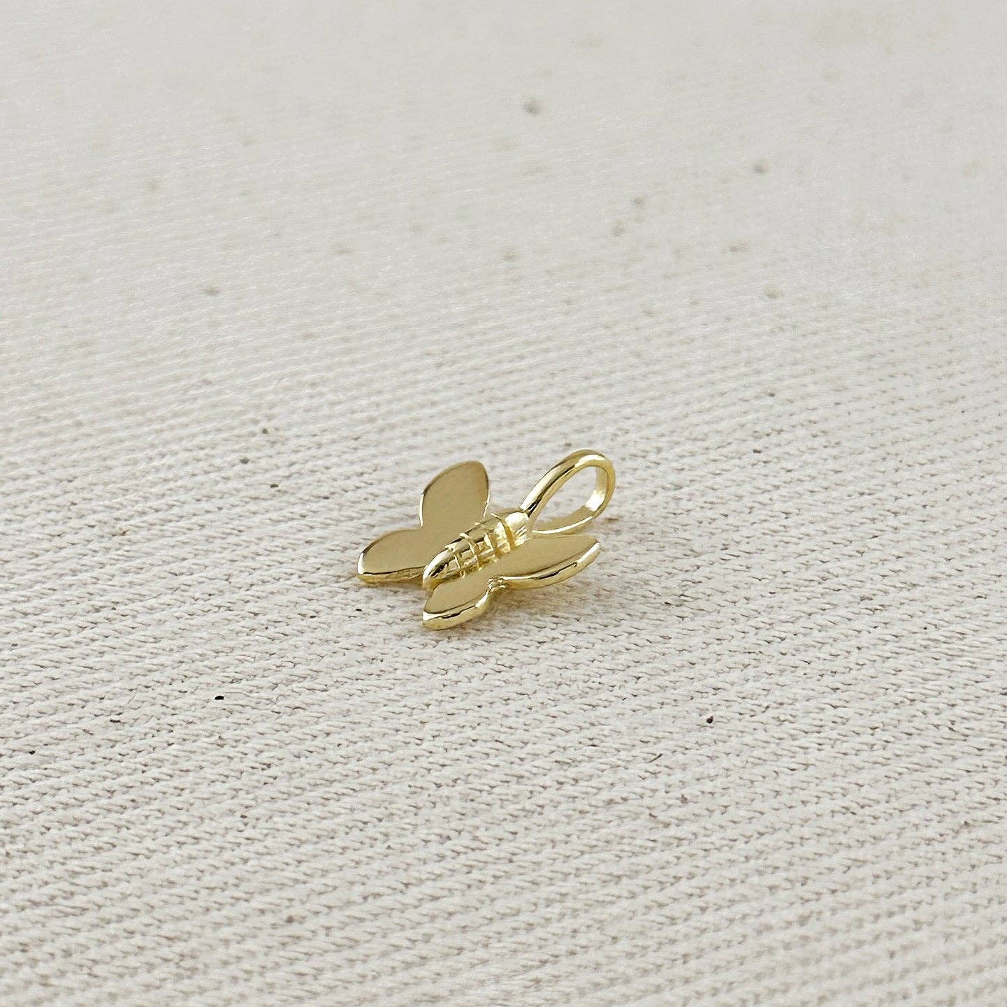 Gold butterfly charm on a light fabric background