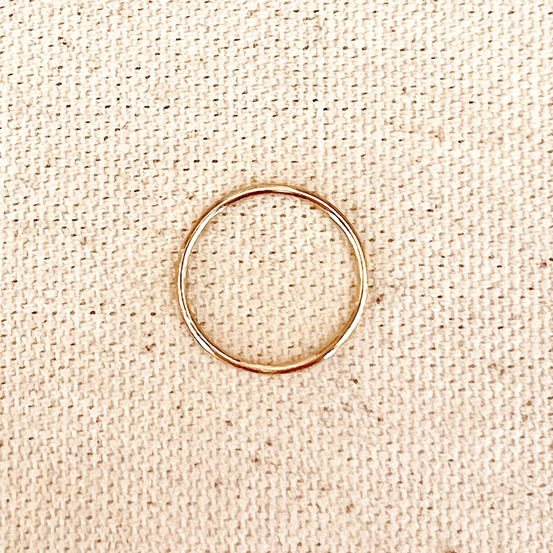 Gold ring on a beige textured fabric background. 1mm Plain Stackable Ring: Size 6 in 14k Gold Filled. 