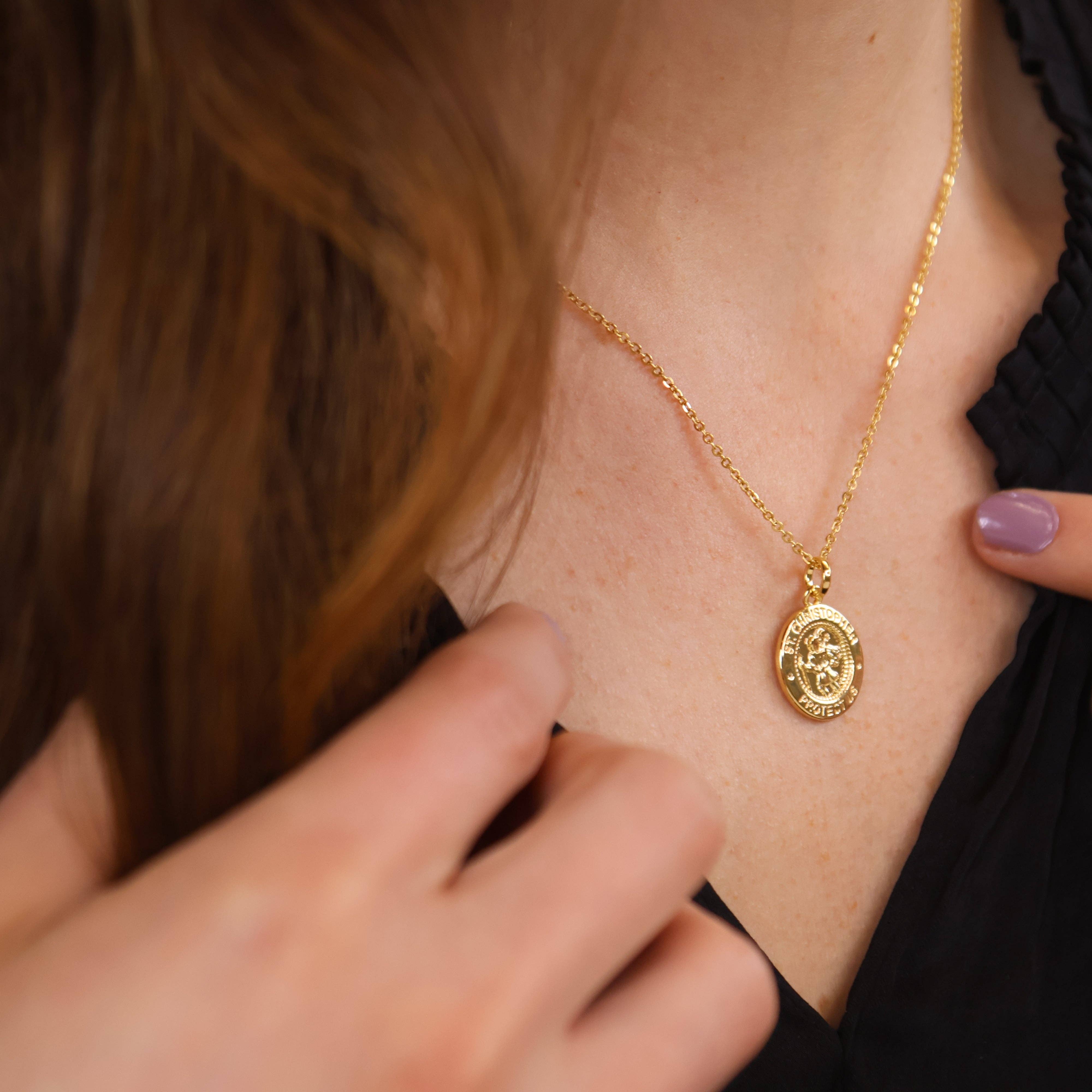 Gold necklace with a pendant worn by a person, close-up shot. Shop Rutledge Exchange for curated vintage and jewelry in Camden, SC.&nbsp;