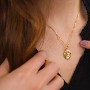 Gold necklace with a pendant worn by a person, close-up shot. Shop Rutledge Exchange for curated vintage and jewelry in Camden, SC.&nbsp;