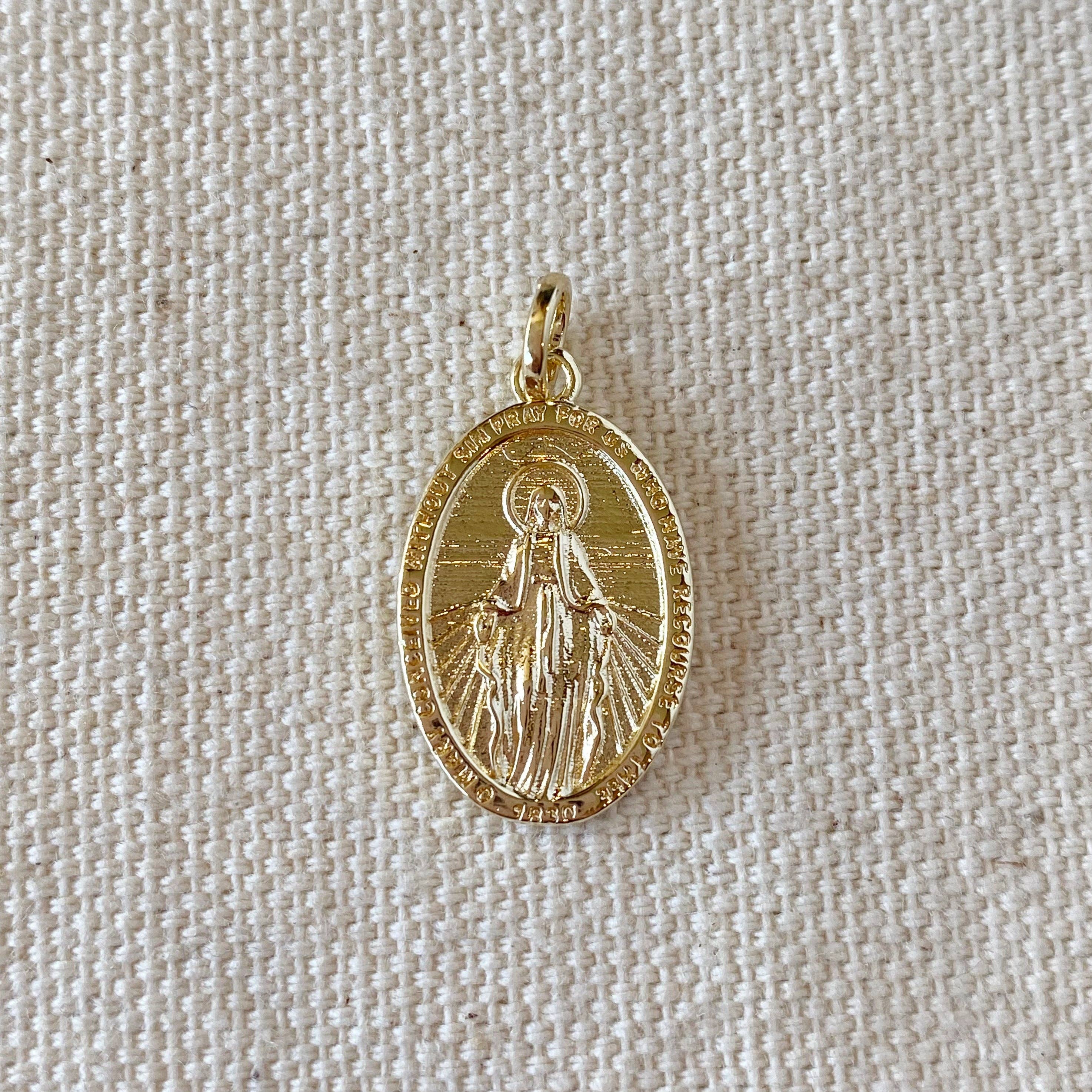 Gold pendant with a religious figure on a beige fabric background. 
Shop Rutledge Exchange for curated vintage and jewelry in Camden, SC.&nbsp;