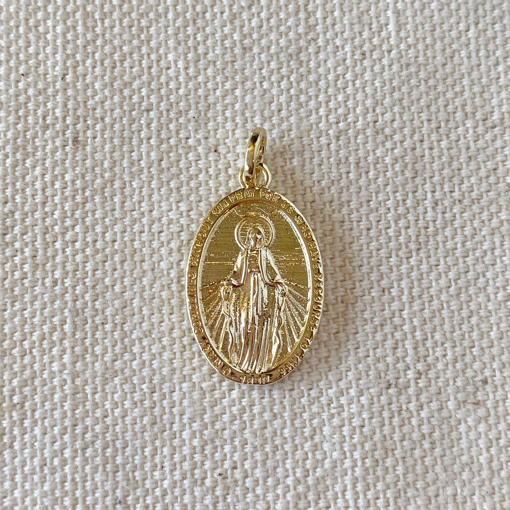 Gold pendant with a religious figure on a beige fabric background. 
Shop Rutledge Exchange for curated vintage and jewelry in Camden, SC.&nbsp;