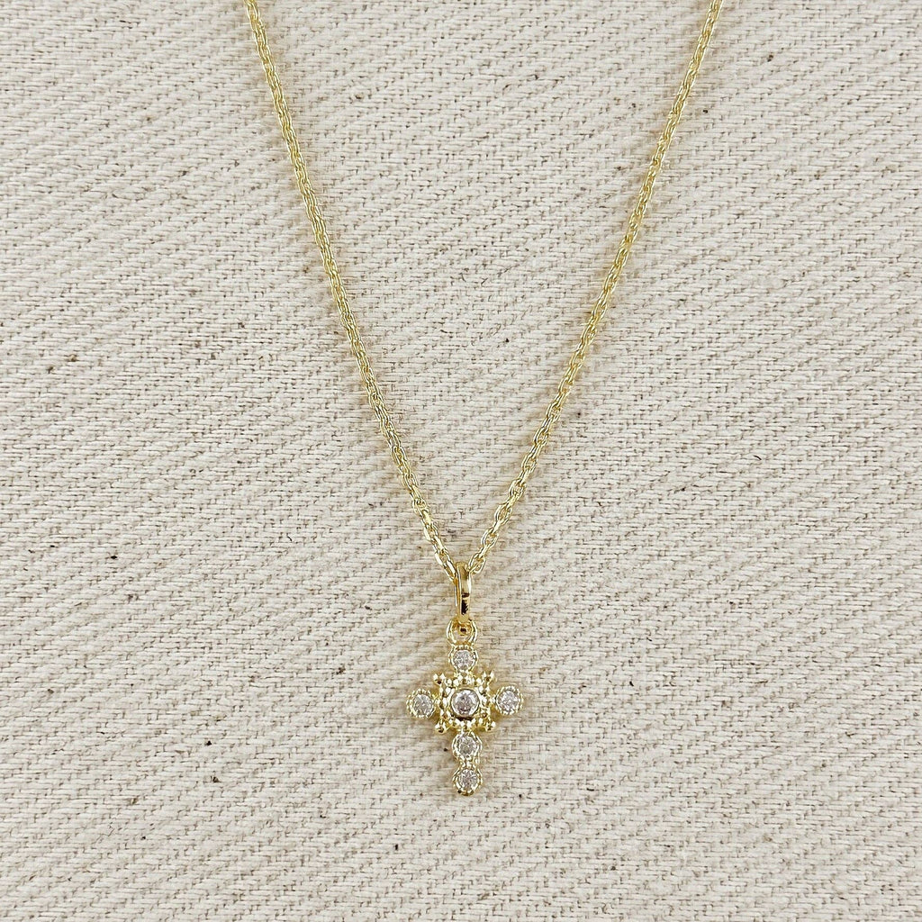 Gold necklace with a star-shaped pendant on a textured beige background. Cross Necklace with Bezel Set CZs in 18k Gold Filled