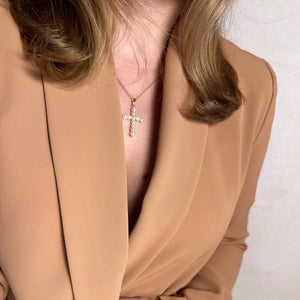 Person wearing a beige blazer with a cross necklace. Shop Rutledge Exchange for curated vintage and jewelry in Camden, SC.