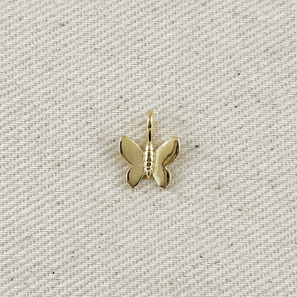 Gold butterfly pendant on a textured beige background