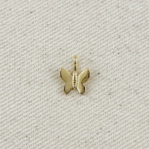 Gold butterfly pendant on a textured beige background