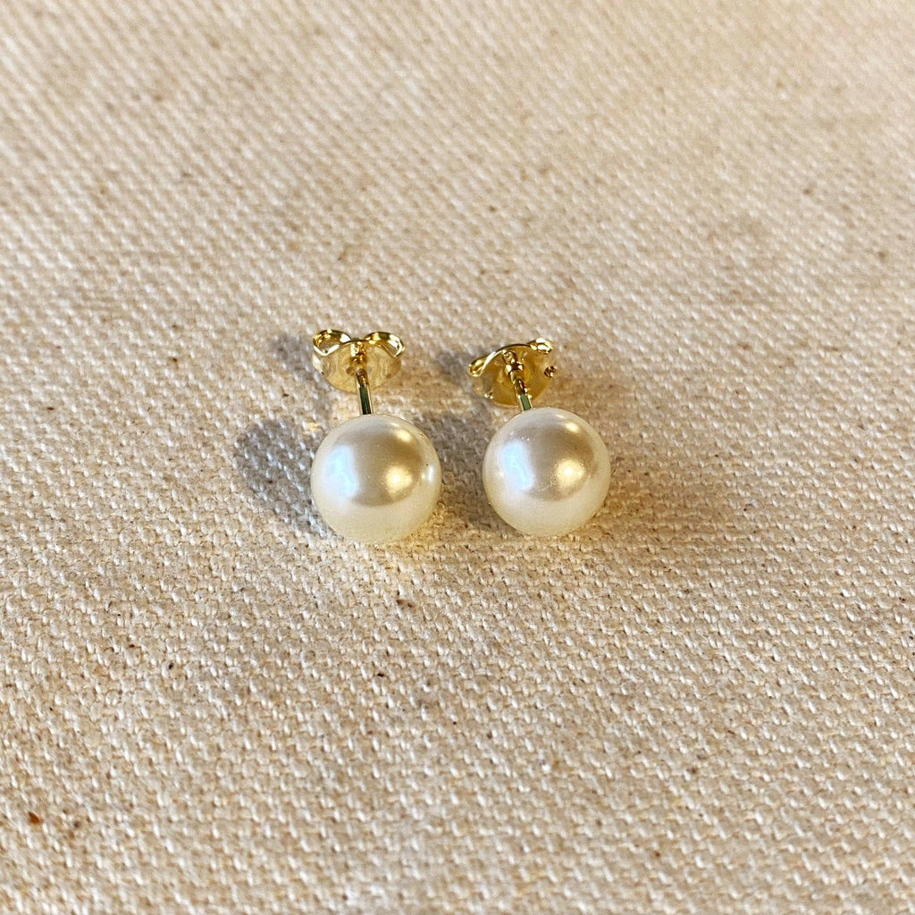 Pair of pearl earrings with gold posts on a beige fabric background. Shop Rutledge Exchange for curated vintage and jewelry in Camden, SC.