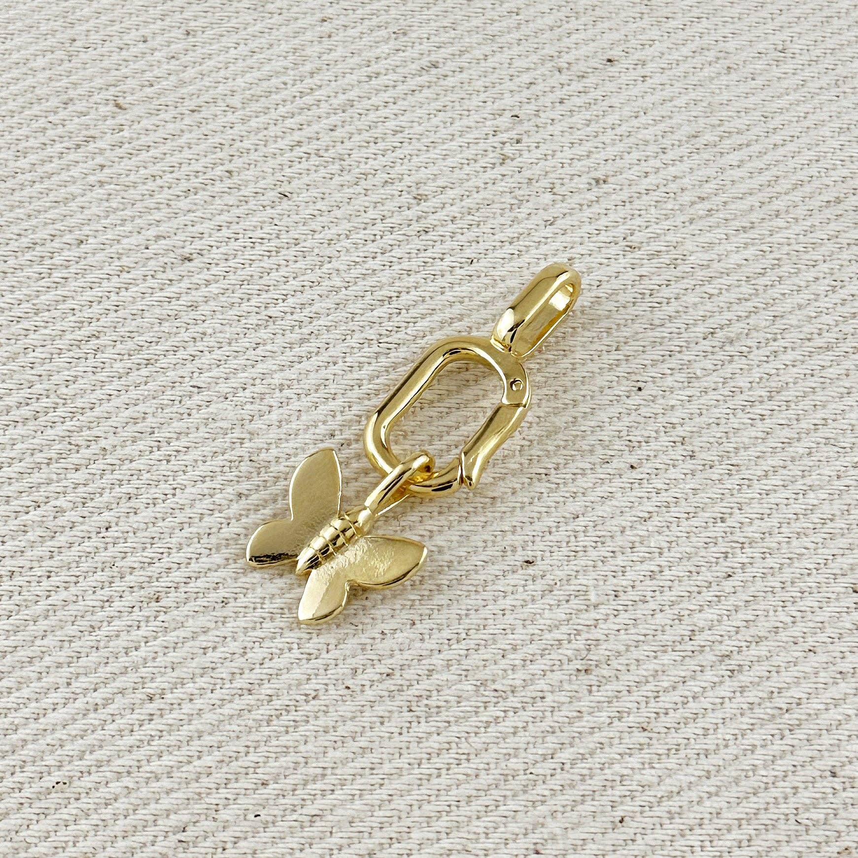 Gold butterfly charm on a textured beige background