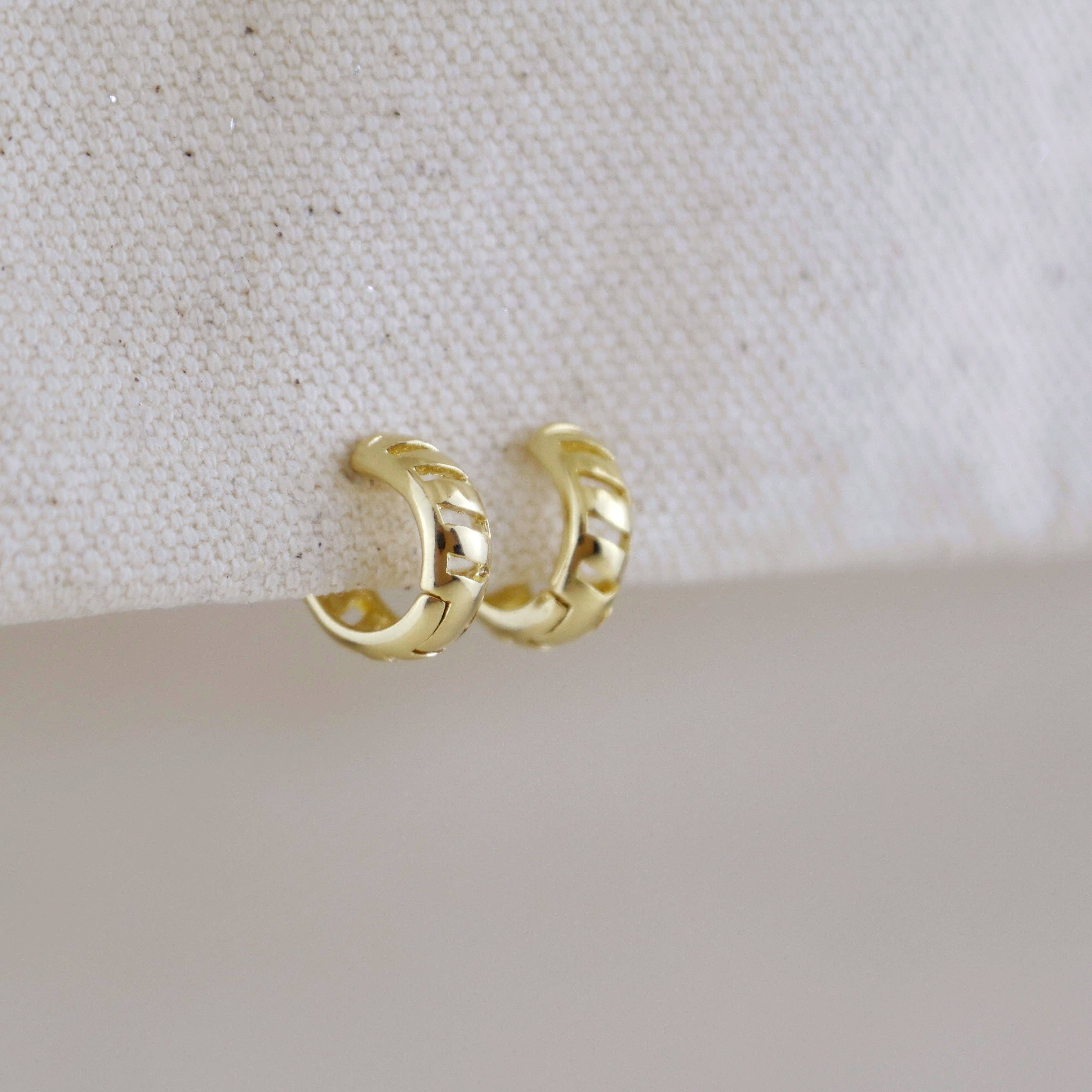 Gold hoop earrings on a textured beige surface. Shop Rutledge Exchange for curated vintage and jewelry in Camden, SC.