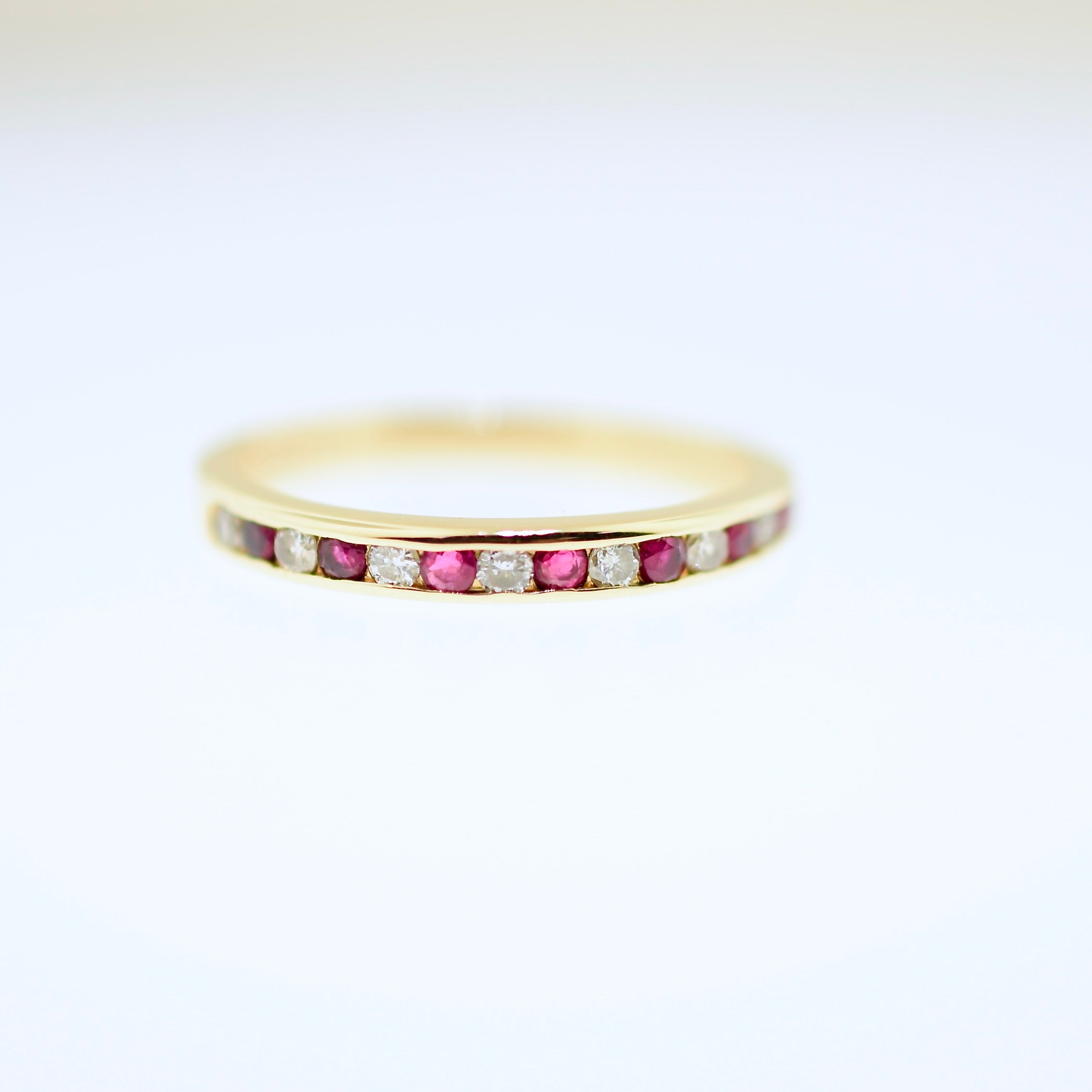 Gold ring with embedded red and clear stones on a white background. Shop curated jewelry and antiques at Rutledge Exchange in Camden, SC.