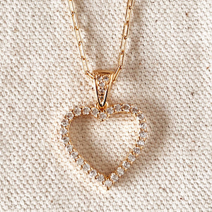 Heart-shaped diamond pendant on a gold chain against a beige fabric background. Shop Rutledge Exchange for curated vintage and jewelry in Camden, SC.