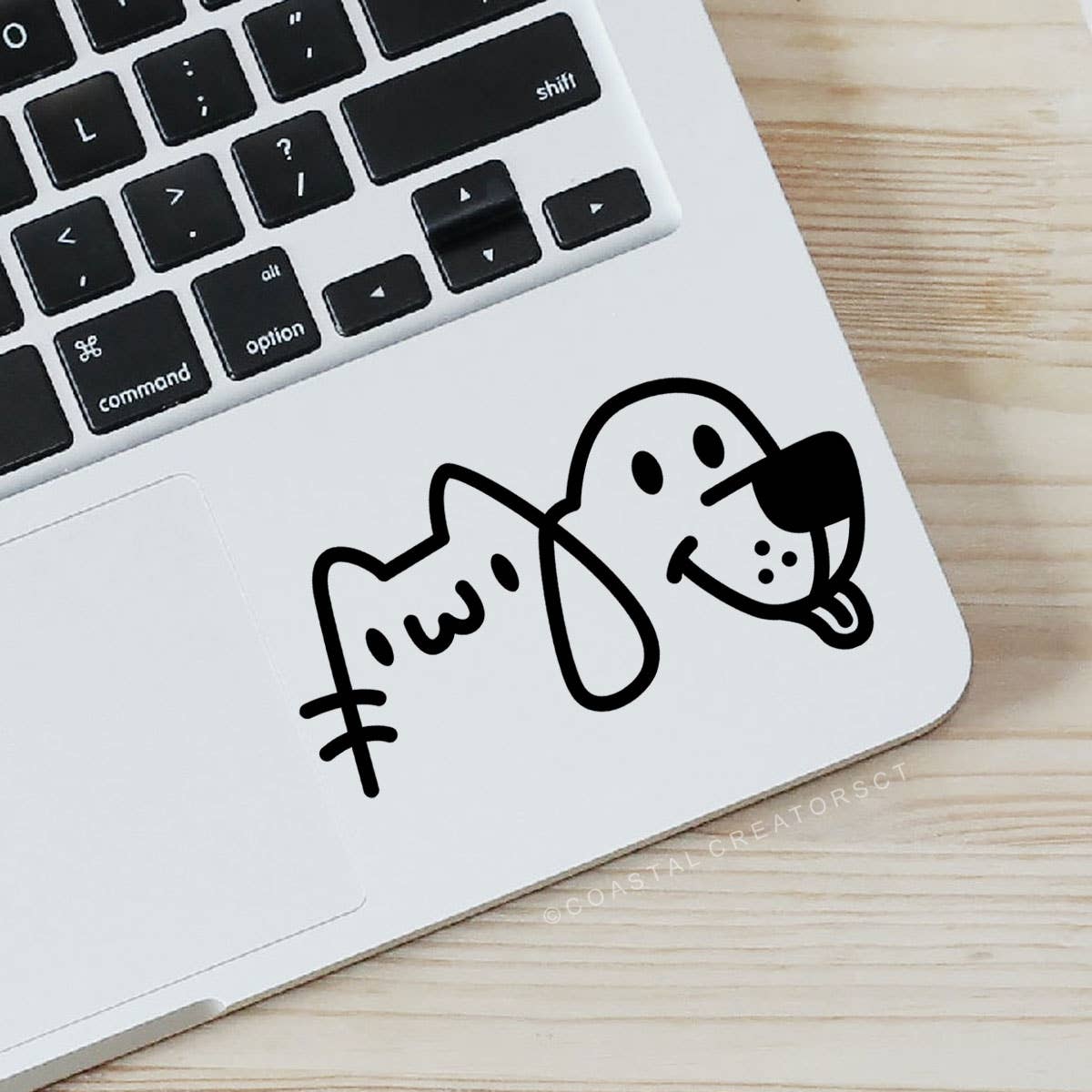 Laptop with a sticker of a cat and dog on a wooden surface. Rutledge Exchange is a boutique jewelry and antique store in Camden, SC. &nbsp;