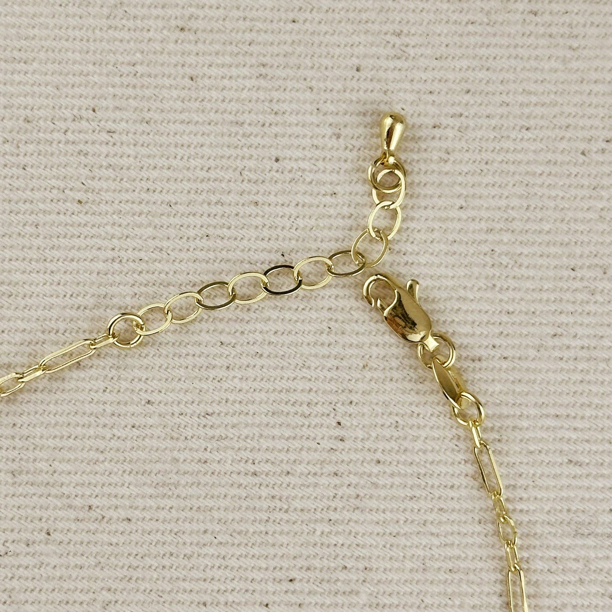 Gold chain necklace on a beige fabric background. Shop Rutledge Exchange for curated vintage and jewelry in Camden, SC.