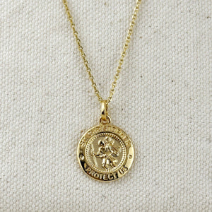 Gold necklace with a circular pendant on a light gray background. Shop Rutledge Exchange for curated vintage and jewelry in Camden, SC.&nbsp;