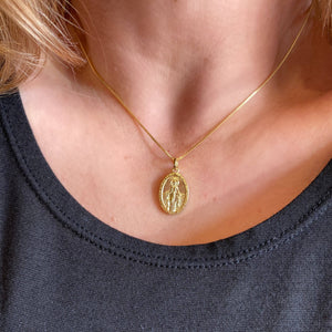 Gold necklace with a pendant worn by a person against a dark background. 
Shop Rutledge Exchange for curated vintage and jewelry in Camden, SC.&nbsp;