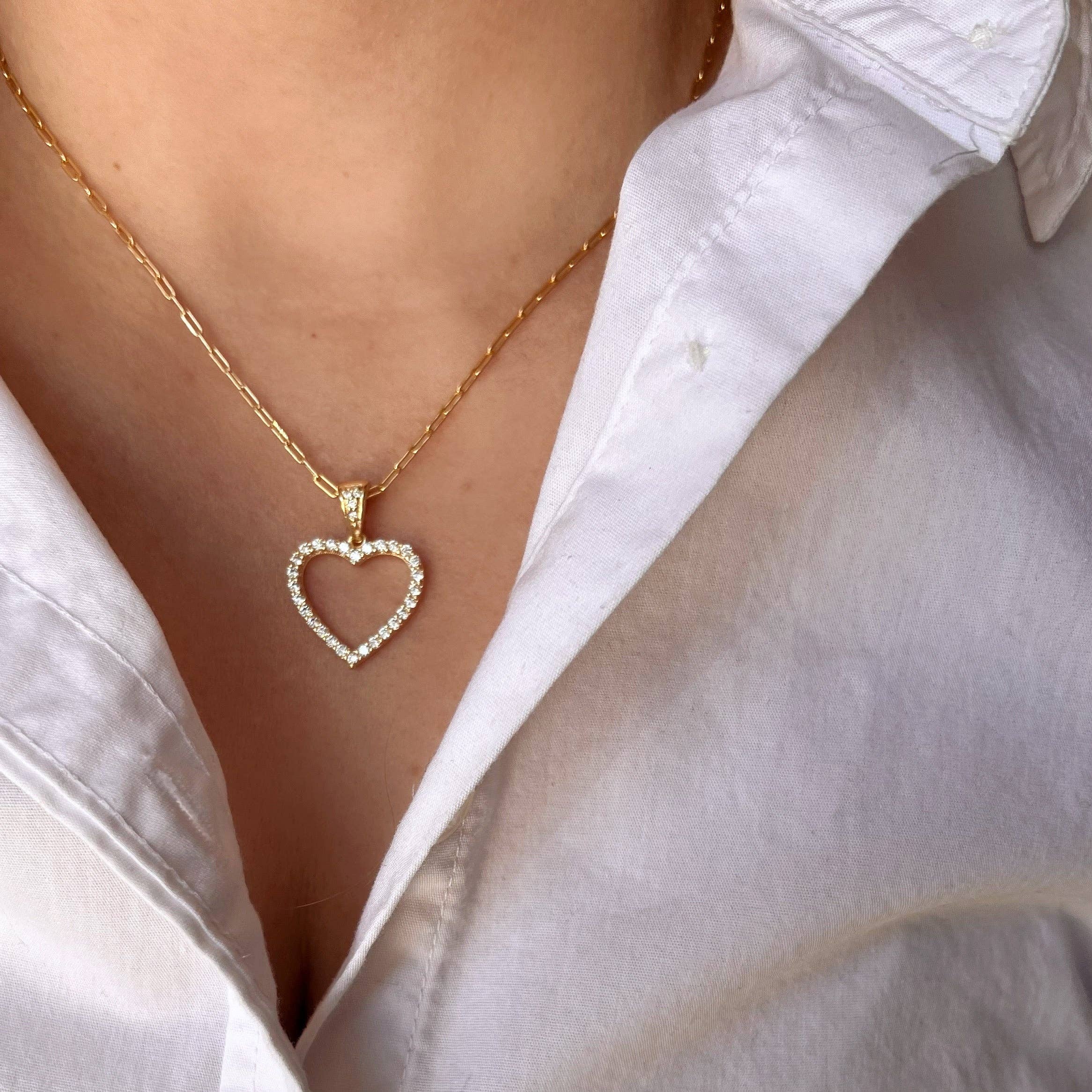 Gold heart-shaped necklace worn by a person in a white shirt. Shop Rutledge Exchange for curated vintage and jewelry in Camden, SC.