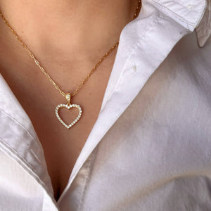 Gold heart-shaped necklace worn by a person in a white shirt. Shop Rutledge Exchange for curated vintage and jewelry in Camden, SC.
