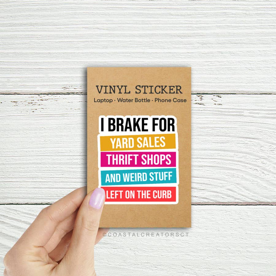 Vinyl sticker with colorful text on a cardboard backing held by a hand against a wooden background. Rutledge Exchange is a boutique jewelry and antique store in Camden, SC. 