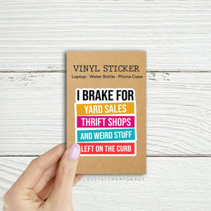 Vinyl sticker with colorful text on a cardboard backing held by a hand against a wooden background. Rutledge Exchange is a boutique jewelry and antique store in Camden, SC. 