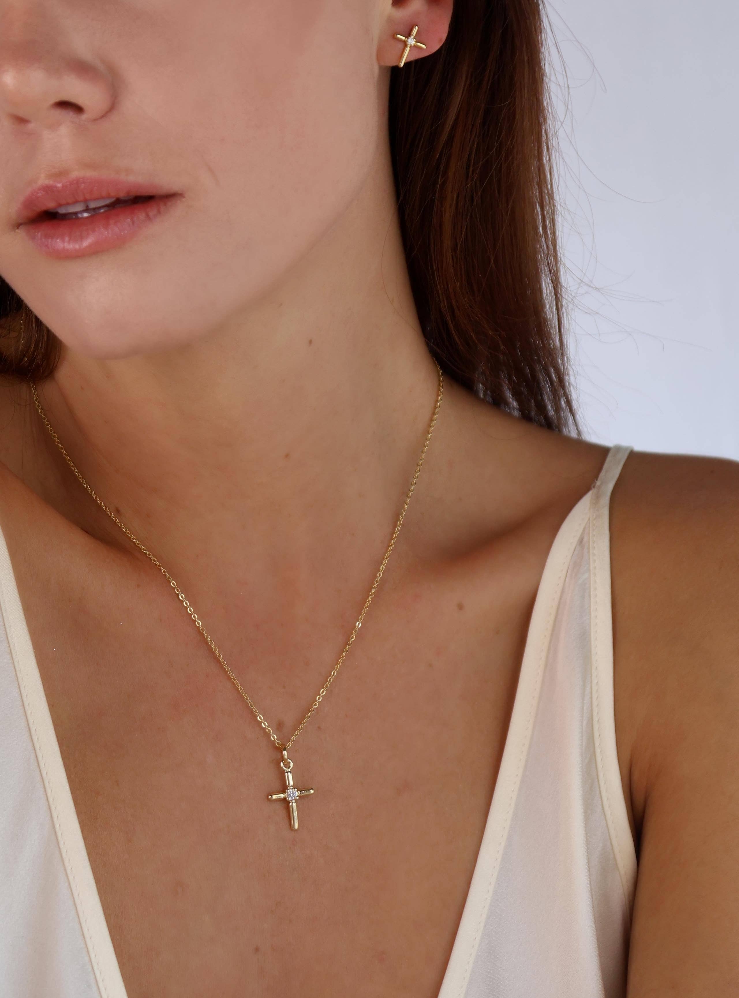 Close-up of a person wearing a gold necklace with a cross pendant. Shop Rutledge Exchange for curated vintage and jewelry in Camden, SC.