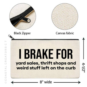 Canvas pouch with text 'I brake for yard sales, thrift shops and weird stuff left on the curb' featuring black zipper and fabric details.