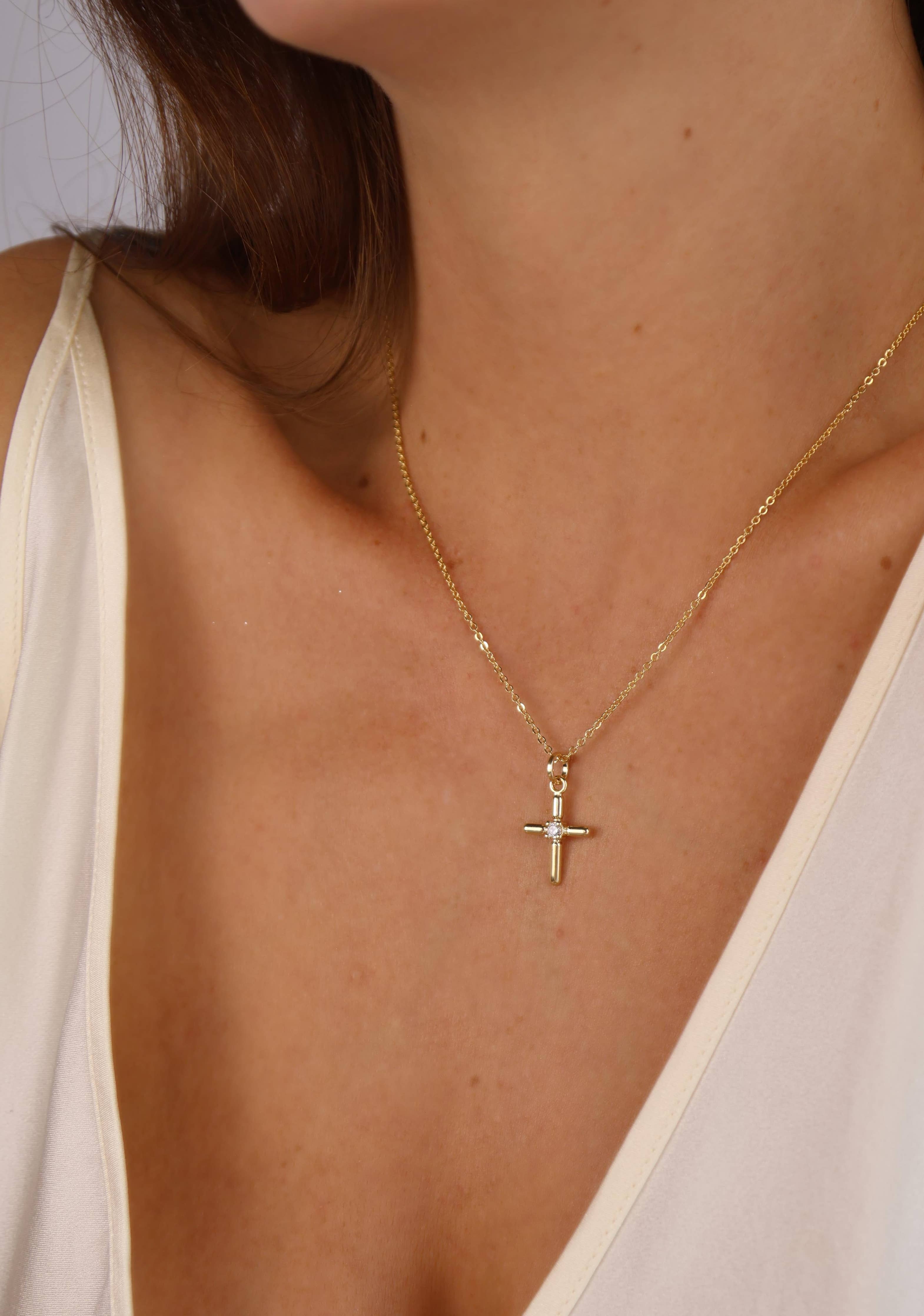 Gold necklace with a cross pendant worn by a person. Shop Rutledge Exchange for curated vintage and jewelry in Camden, SC.