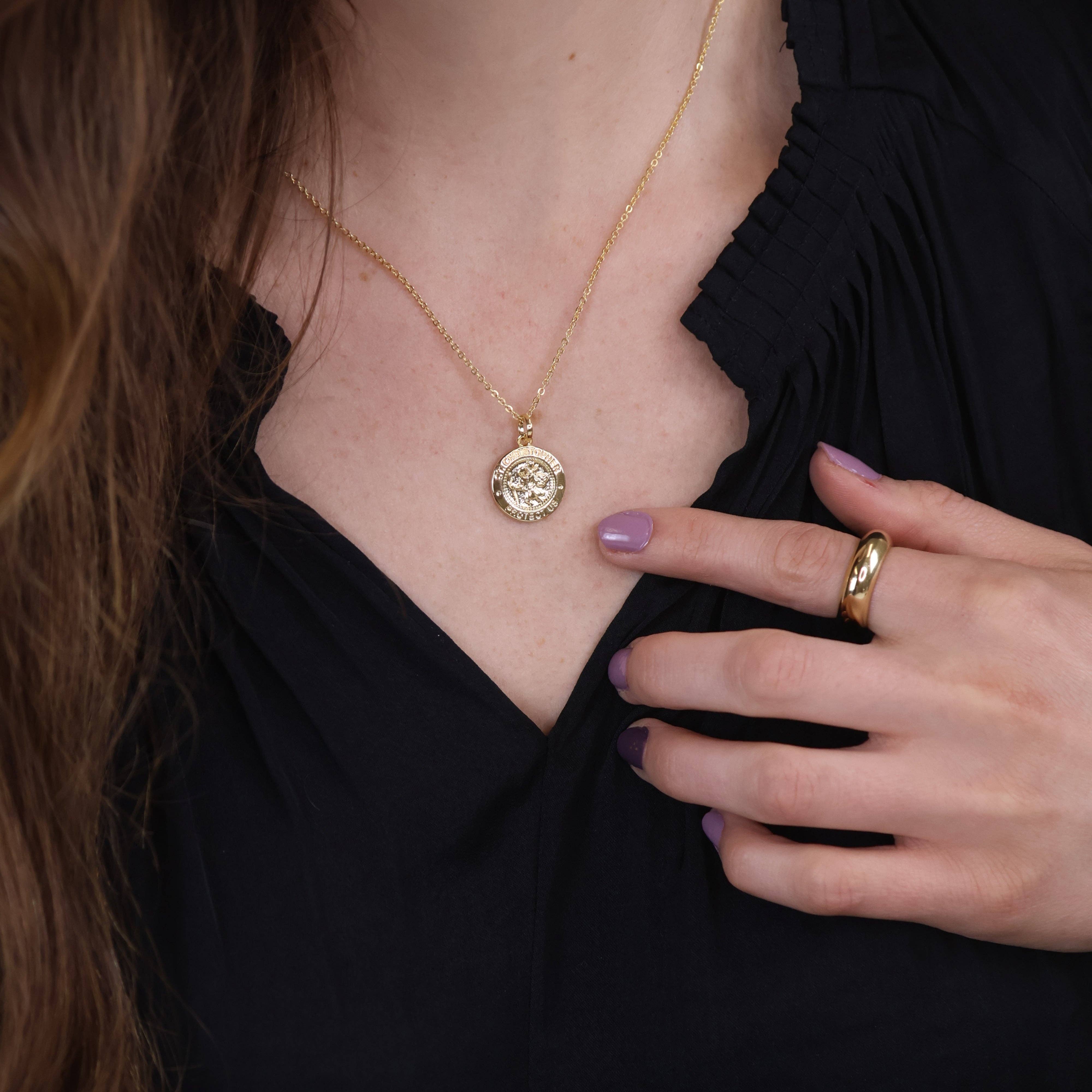 Person wearing a gold necklace with a pendant and a matching ring, against a dark background. Shop Rutledge Exchange for curated vintage and jewelry in Camden, SC.&nbsp;
