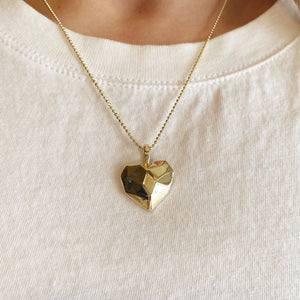 Gold heart-shaped pendant necklace on a white shirt . Shop Rutledge Exchange for curated vintage and jewelry in Camden, SC.