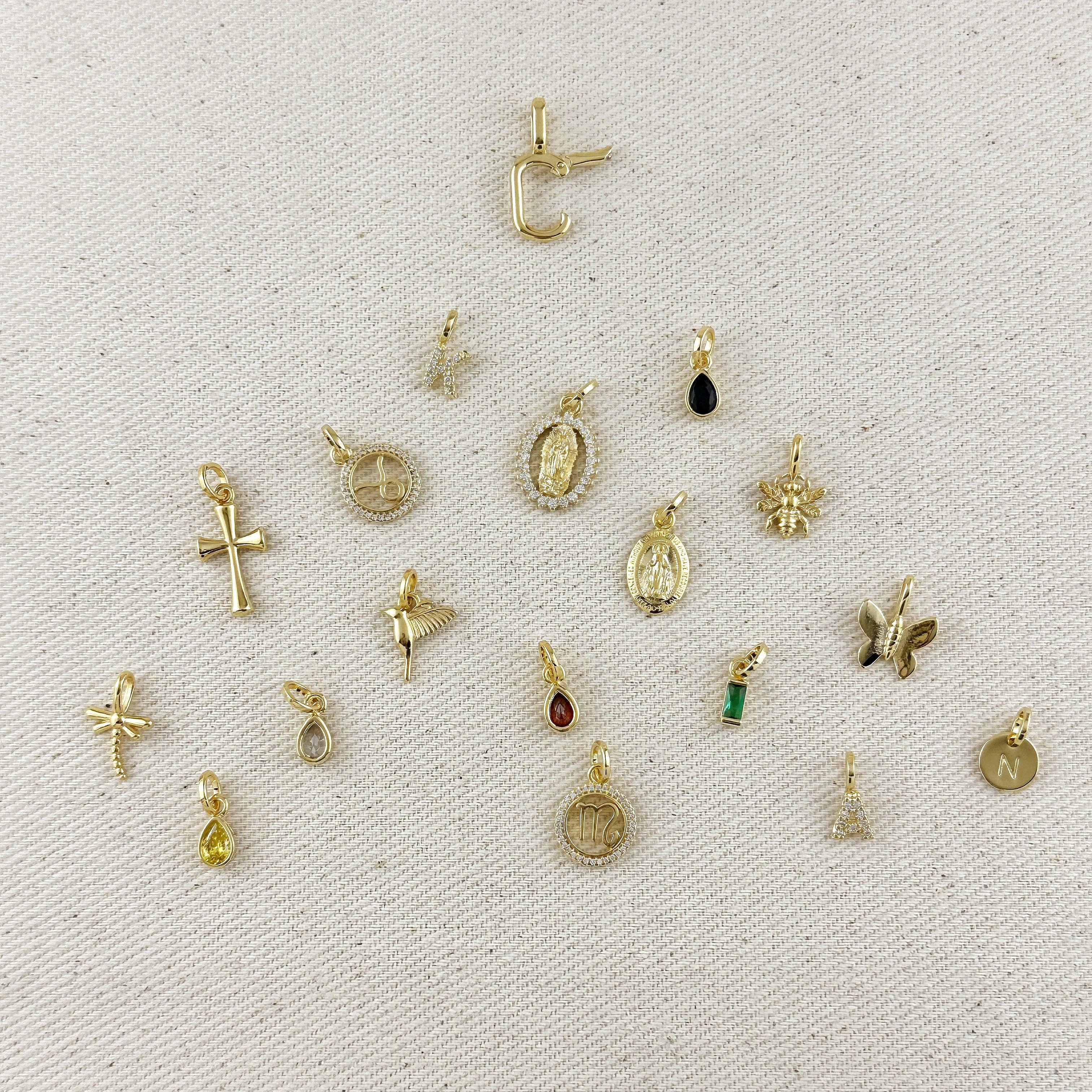 Collection of various gold pendants on a textured beige background