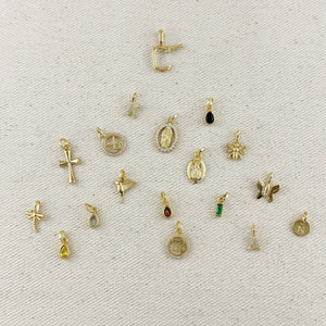 Collection of various gold pendants on a textured beige background