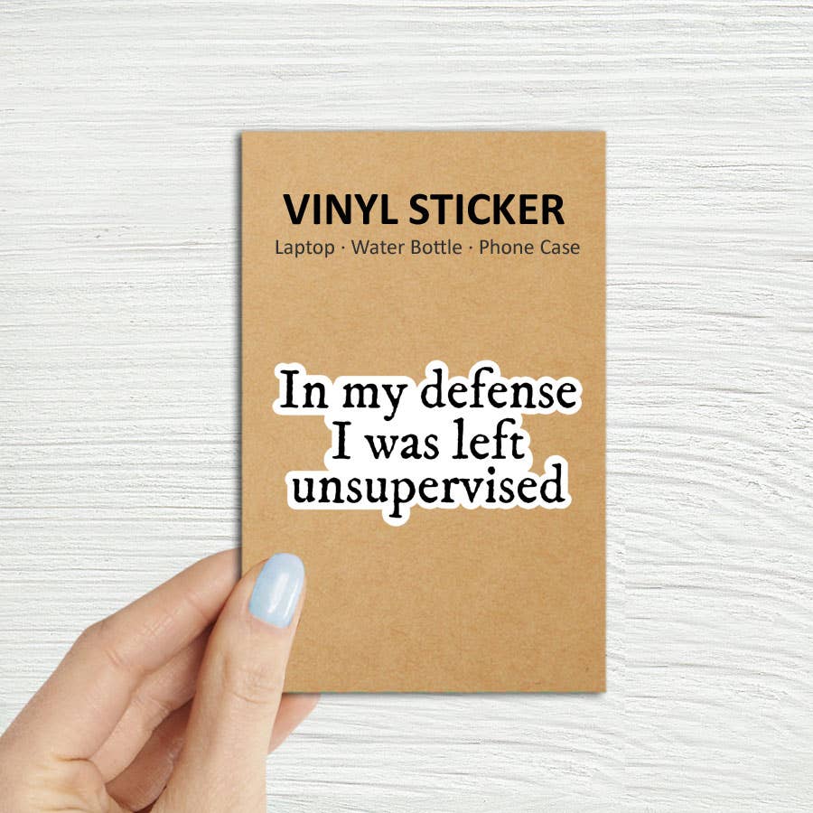 Vinyl sticker packaging with text 'In my defense I was left unsupervised' on a textured white background In My Defense I Was Left Unsupervised Laptop Kindle Sticker