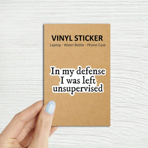 Vinyl sticker packaging with text 'In my defense I was left unsupervised' on a textured white background In My Defense I Was Left Unsupervised Laptop Kindle Sticker